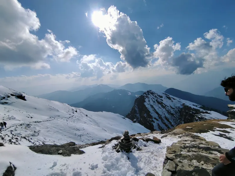Snow slope and a jagged peak under drifting clouds