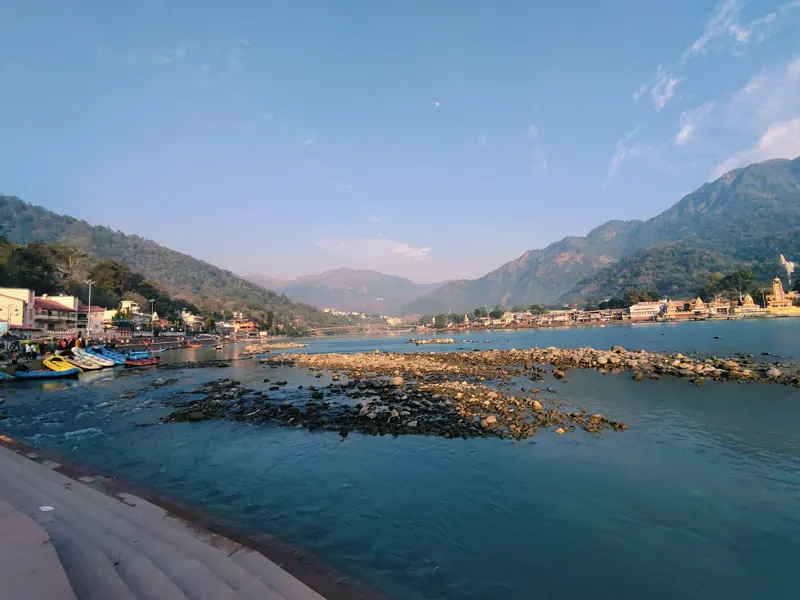 The Ganga flowing past rocks and ghats with hills behind
