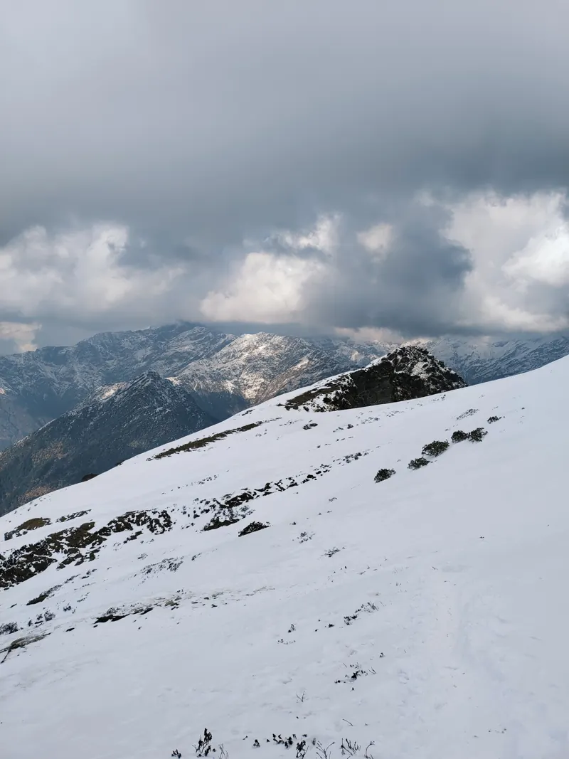 Steep snowfield rising to a ridge under grey cloud
